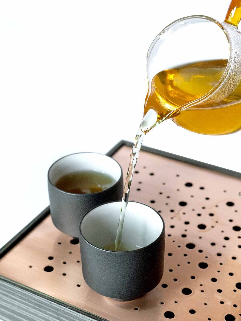 Tea is poured in two little cups, western style tea brewing