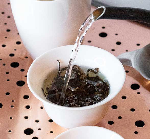 Water is poured in gaivan, full of tea leaves. Gong Fu style tea brewing.